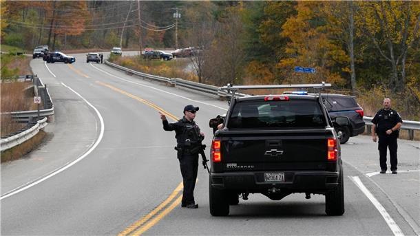 Nach Attacke mit 18 Toten: Großfahndung nach Täter in Maine Polizeibeamte sprechen bei einer Straßensperre während der Fahndung nach einem Schusswaffenangriff mit einem Autofahrer.