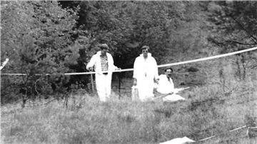 Polizeibeamte untersuchen im Wald in der Göhrde den Auffindeort des ermordeten Paares.