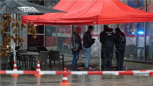 Polizeibeamte untersuchen unter einem Zeltdach den Tatort in Gummersbach.