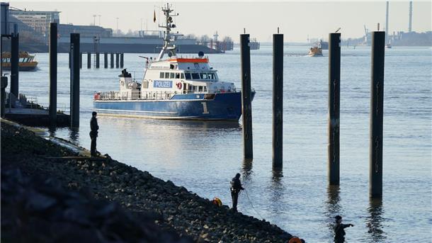Polizeitaucher und Polizeibeamte bei der Suche nach dem Jungen in der Elbe.