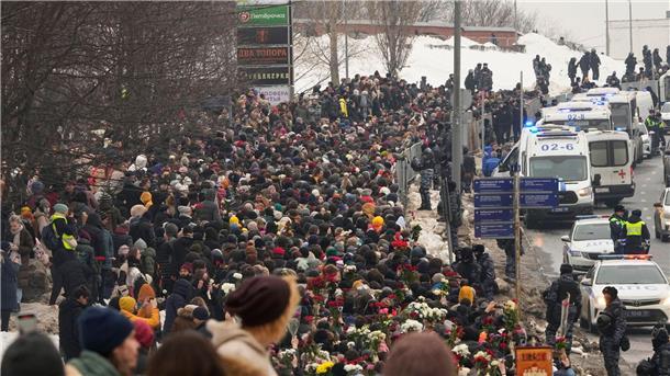 Polizisten beobachten, wie Menschen zur Beerdigungszeremonie des russischen Oppositionellen Nawalny gehen.