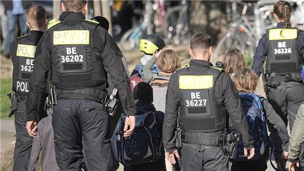 Messerangriff an Schule: Ermittler sprechen von „Zufallstat“ Polizisten geleiten Kinder weg vom Tatort an der Schule in Berlin-Neukölln.