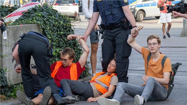 Polizisten halten an der Kreuzung am Stachus in der Münchner Innenstadt Klimaaktivisten der Letzten Generation fest.