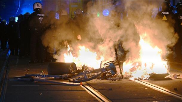 Weitere Krawalle: Leipzig kommt nicht zur Ruhe Polizisten hinter einer brennenden Barrikade.