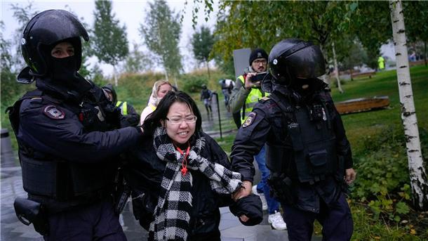 Polizisten in Moskau halten eine Demonstrantin fest.