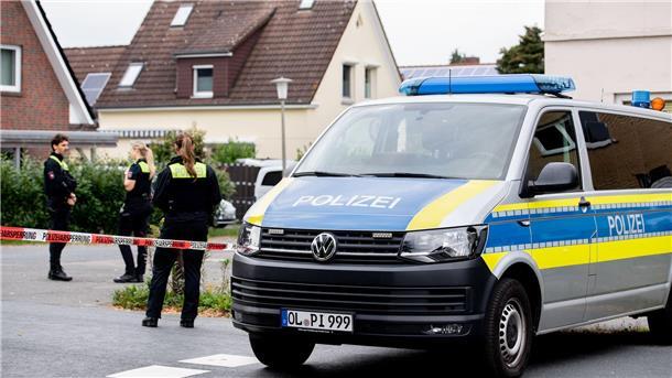 Polizisten sperren den Tatort mit Absperrband und Polizeiautos ab. 