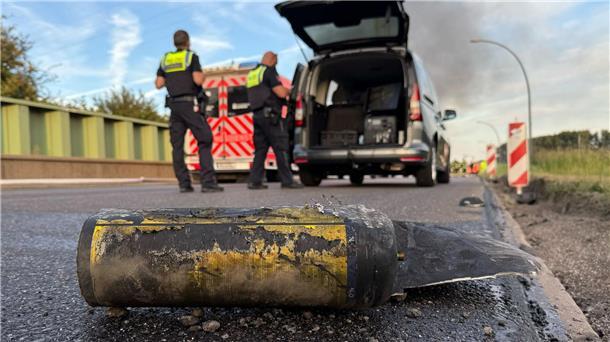 Hunderte Feuerwehrleute löschen Großbrand in Hamburg Polizisten stehen hinter einem Metallbehälter. Trümmerteile sollen bei dem Brand Hunderte Meter weit geflogen sein.
