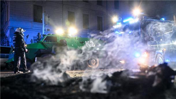 Polizisten stehen hinter einer rauchenden Barrikade im Stadtteil Connewitz in Leipzig.