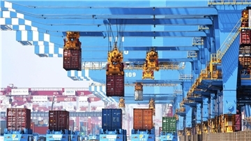 Portalkräne heben Container auf Transporter in einem Hafen in Qingdao in der ostchinesischen Provinz Shandong.