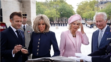 Präsident Emmanuel Macron (l-r) und und seine Ehefrau Brigitte Macron sowie Königin Camilla und König Charles III. von Großbritannien tragen sich während einer Zeremonie am Triumphbogen in Paris ins Goldene Buch ein.