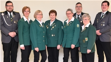 Frauen und Männer in Schützenuniformen stehen nebeneinander in einer Reihe 