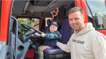 Probesitzen bei der Wremer Feuerwehr: Während sich Papa Marcel Bursky über eine großzügige Spende freut, blüht Söhnchen Theo auf dem Fahrersitz des Feuerwehreinsatzwagens auf.