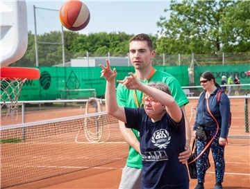 Profi-Basketballer Adrian Breitlauch beteiligt sich als ehrenamtlicher Helfer am Behindertensportfest - und wird natürlich für den Basketball-Stand eingeteilt. Hier unterstützt er Myriam Schütte beim Wurf.