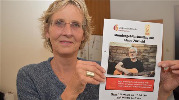 Projekt-Betreuerin Christine Sassen-Schreiber zeigt das Plakat der erfolgreich verlaufenen Auftaktveranstaltung, eines Mundorgel-Nachmittags im September mit Klaus Zurhold