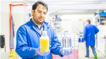 Projektleiter Faraz Rasheed Mir vom ttz zeigt eine Flasche mit Waschwasser von einer Fassadenreinigung und wie der Inhalt nach Vorreinigung und Membranfiltration aussehen soll.