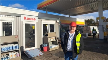 Prokurist Kevin Tilly am provisorischen Klassencontainer der Tankstelle. Am Autohof Wulsdorf wird derzeit gebaut. 