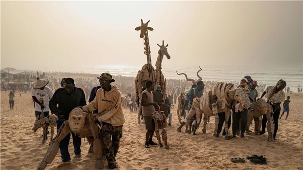 Als Herde gegen den Klimawandel Puppenspieler bewegen die Papptiere an einem Strand im Land Senegal.