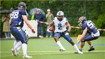Ein American-Football-Spieler trägt den Ball im Laufen nach vorne.