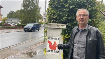 Mann steht vor einem Schild mit Eichhörnchen