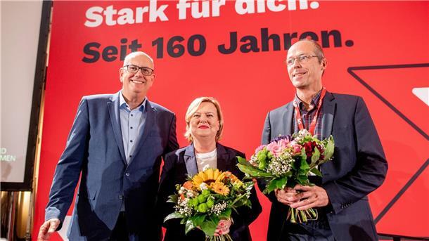 Drei Personen mit Blumen. 