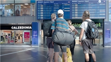 Reisende im Berliner Hauptbahnhof vor einer Info-Tafel mit Zugverbindungen.