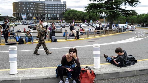 Französische Flughäfen wegen Bombendrohungen gesperrt Reisende warten, während ein französischer Soldat vor dem Flughafen Toulouse-Blagnac patrouilliert.
