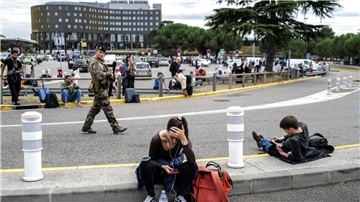 Reisende warten, während ein französischer Soldat vor dem Flughafen Toulouse-Blagnac patrouilliert.