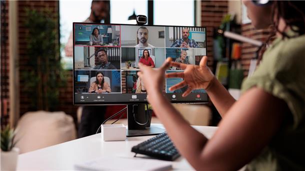 Eine junge Frau videotelefoniert mit ihrem Team.