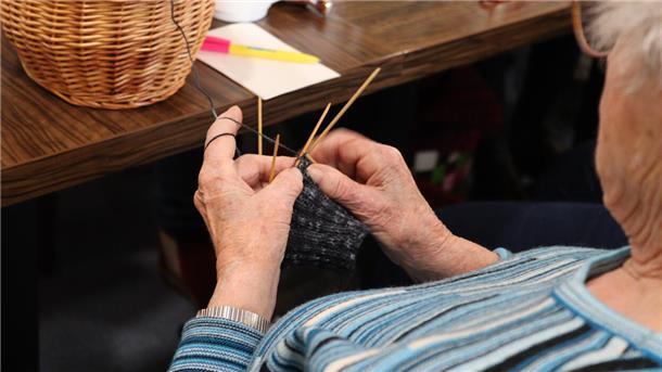 Frau im blauen Streifen-Pullover mit Sticknadeln