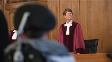 Renate Philipp, Versitzende Richterin am Bundesverwaltungsgericht, steht während der Verhandlung im Gerichtssaal in Leipzig. Im Vordergrund sitzt einer Kläger im Rollstuhl.
