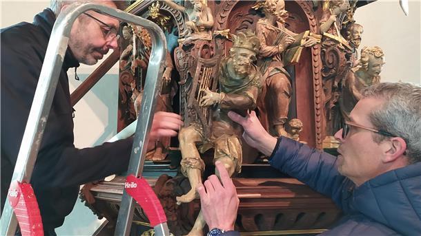 Restaurator Uwe Pleninger (links) und Kirchbauvereins-Vorsitzender Ibeling van Lessen justieren an der Kanzel die Figur des Königs David.