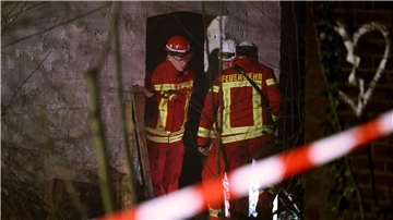 Rettungskräfte beraten vor eine Gebäude, in dem sich Personen in einem Tunnel verschanzt haben.