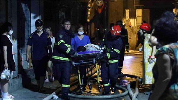Rettungskräfte tragen eine Person aus dem brennenden Gebäude in Hanoi.