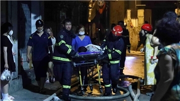 Rettungskräfte tragen eine Person aus dem brennenden Gebäude in Hanoi.