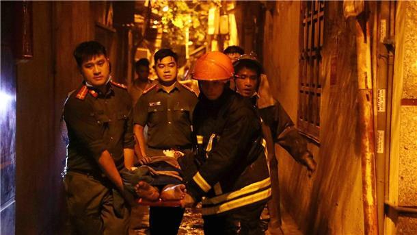 Rettungskräfte tragen eine Person aus einem brennenden Gebäude in der vietnamesischen Hauptstadt Hanoi.