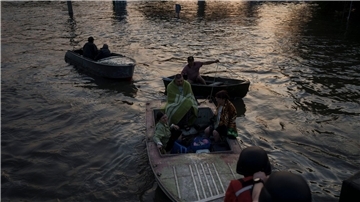 Rettungskräfte versuchen, Boote mit Bewohnern abzuschleppen.