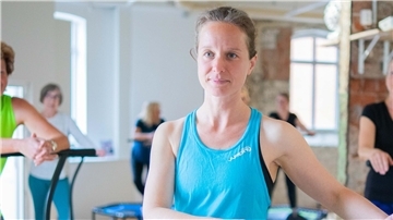 Mehrere Frauen stehen in einem Trainingsraum auf Trampolinen.