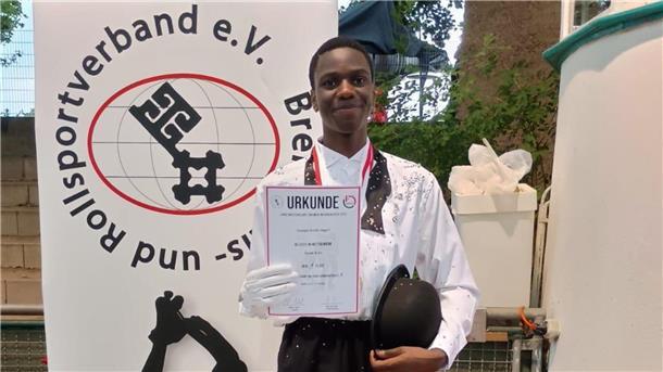 Rollkunstläufer Joseph Asafo-Agyei lächelt und hält seine Urkunde in die Kamera.