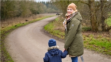 Eine Frau mit Kind auf steht auf einem Feldweg.
