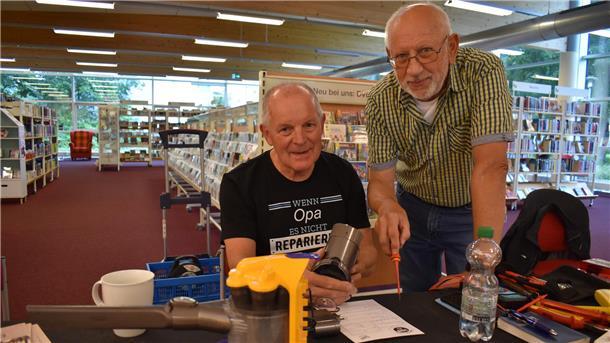 Rüdiger Tetzlaff (links) und Rainer Draheim reparieren einen Staubsauger