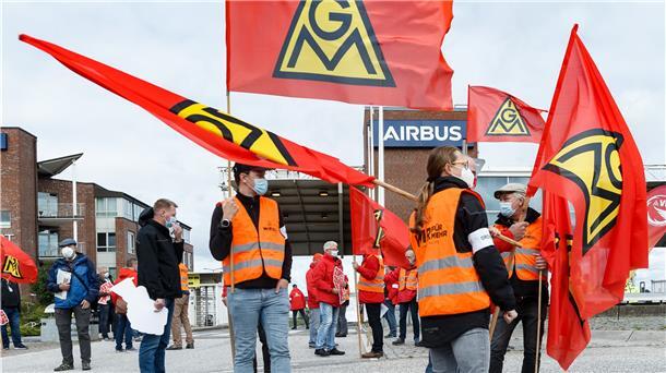 Mitarbeiter von Airbus streiken mit Fahnen.