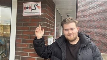 Mann zeigt auf Schild mit Kameraüberwachung