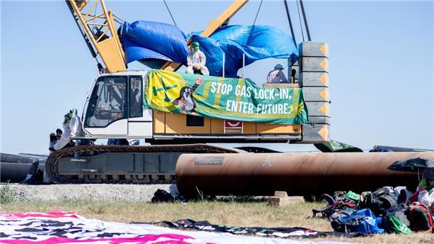 Ein Transparent mit der Aufschrift „Stop Gas Lock-In, Enter Future.“ hängt an einem Kran auf der Baustelle für die geplante Gaspipeline am Jade-Weser-Port.