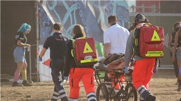 Ein Team von Sanitätern transportiert einen Patienten auf einer Trage über das Festivalgelände 