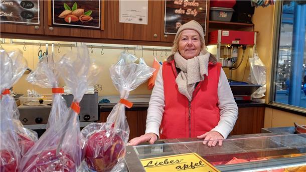 Eine alte Frau verkauft süße Äpfel auf dem Weihnachtsmarkt