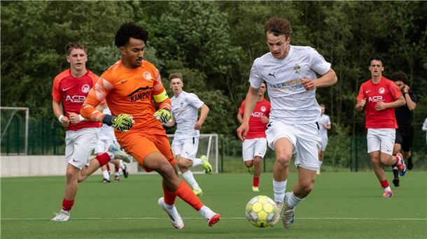 Mehrere Männer in Sporttrikots laufen hinter einem Ball her.