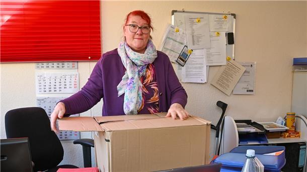 Eine Frau in einem Büro, die einen Karton packt. 