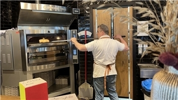 Ein Mann schiebt ein Ciabatta in den Ofen.