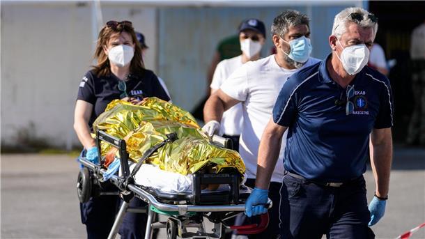 Sanitäter transportieren einen verletzten Überlebenden des Bootsunglücks zu einem Krankenwagen im Hafen der griechischen Stadt Kalamata.
