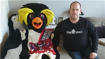 Sascha Wolter mit dem Kralli-Kostüm auf dem heimischen Sofa. Das Maskottchen der Fischtown Pinguins darf derzeit nicht in die Eishalle.